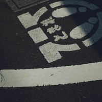 道路の歩道に描かれた白いとまれ標示と横断歩道の写真