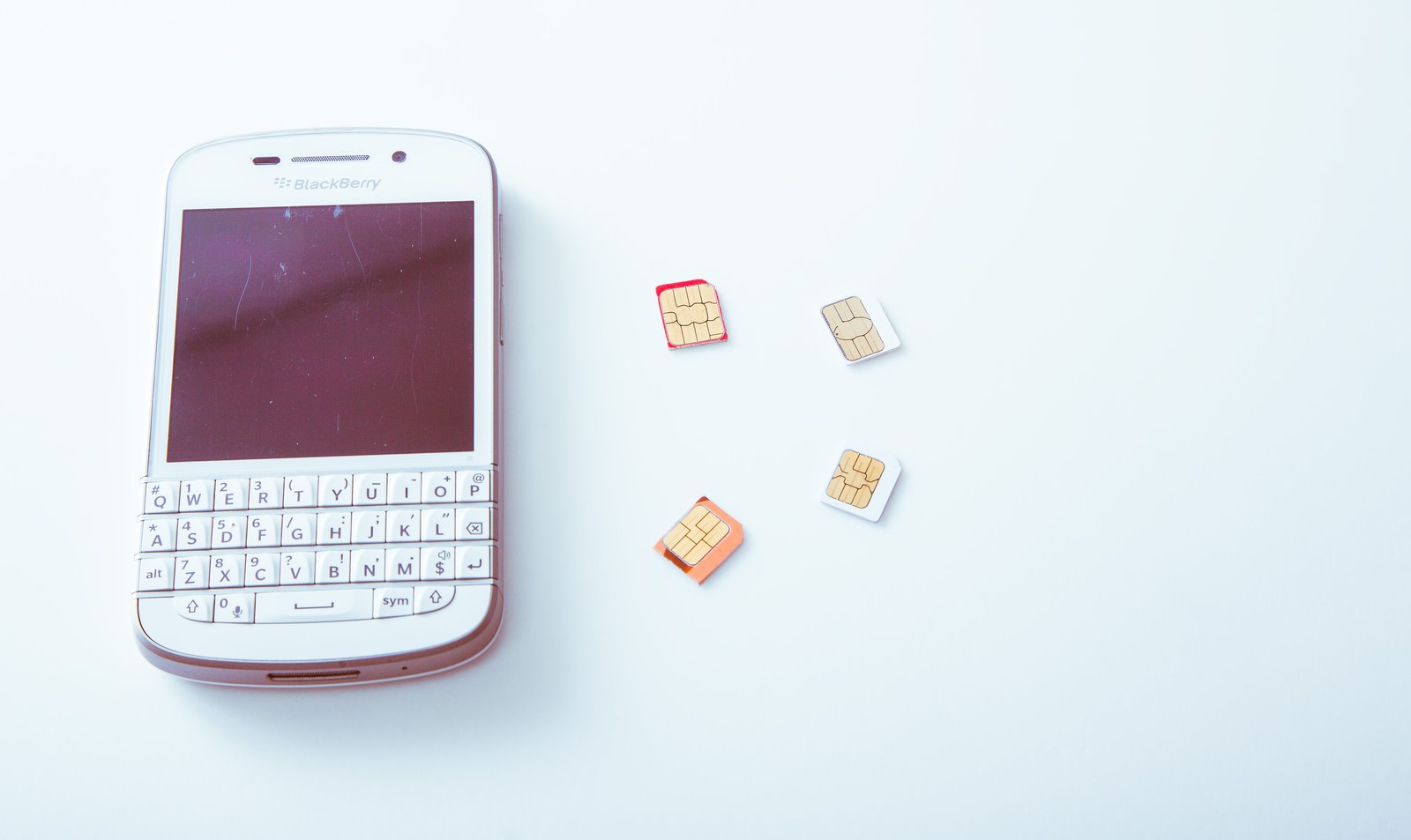 白いBlackBerryと4枚のSIMカード