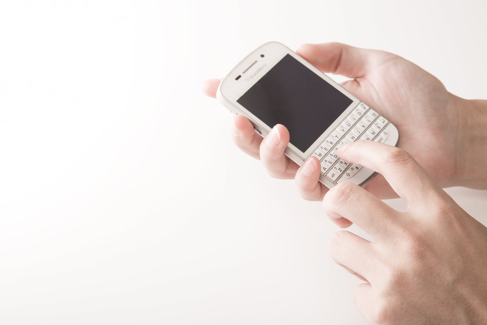 白いスマートフォンのキーボードを両手で操作している