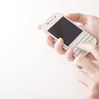 白いスマートフォンを両手で操作する人のビジネスシーンの写真