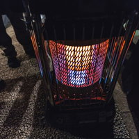 石油ストーブの周りに集まる人の足元（夜間）の写真