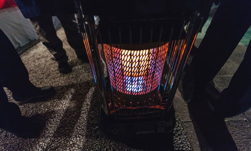 石油ストーブの周りに集まる人の足元（夜間）