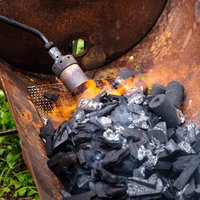 トーチバーナーで黒い木炭に火をおこす瞬間の写真