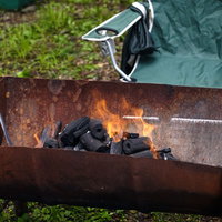 赤い炎が上がる半分にしたドラム缶のBBQグリルの写真