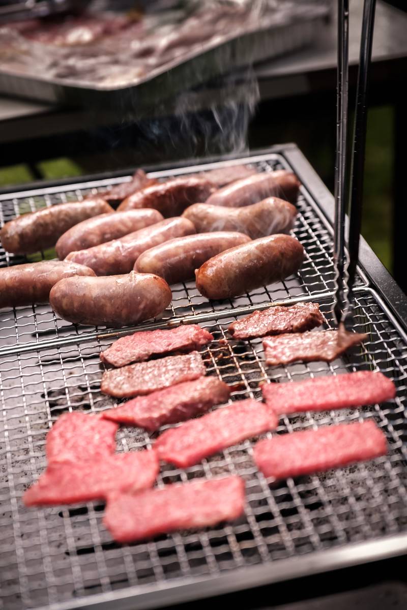 炭火の網の上で焼かれているソーセージと焼肉