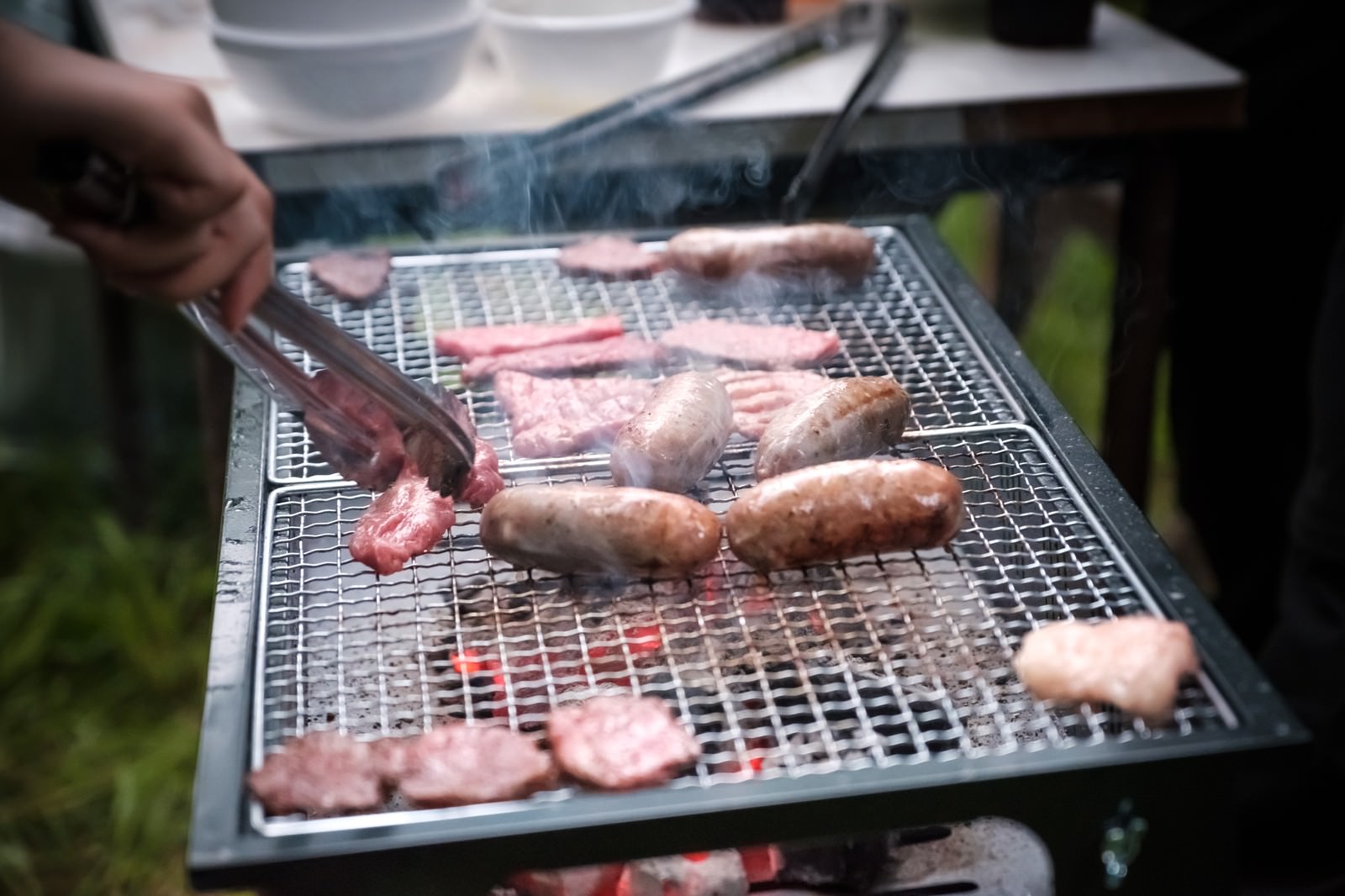 炭火の網でソーセージとウィンナーを焼いている様子
