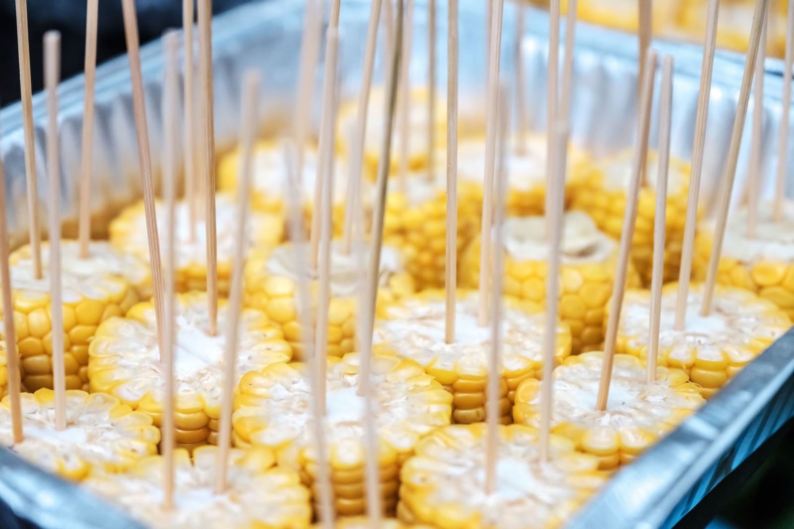 串に刺さった黄色いとうもろこしが透明ケースに整列している
