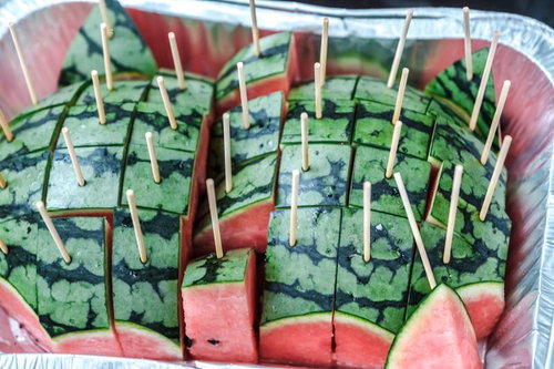 ピンクのかごに入った串がささったスイカ、竹串を刺した一口サイズ
