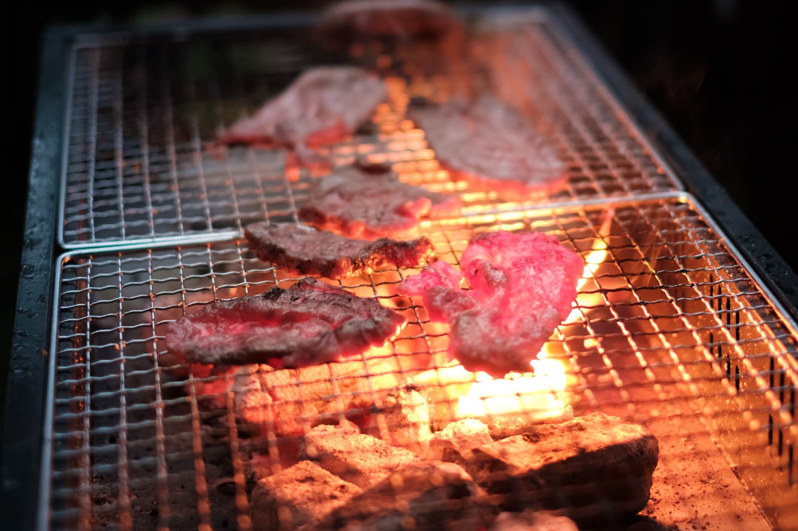 炭火で網焼きされている赤く焼けた肉