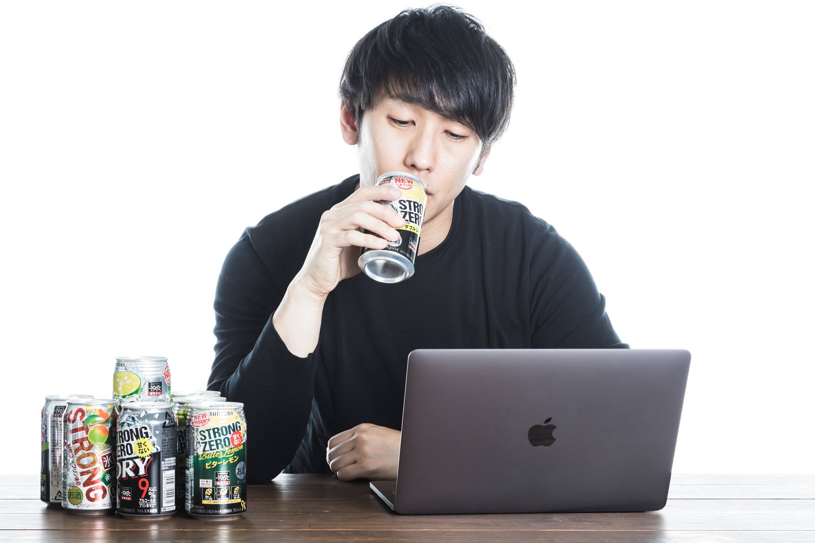 缶チューハイを手に持ちながらノートパソコンを操作する男性［モデル：大川竜弥］