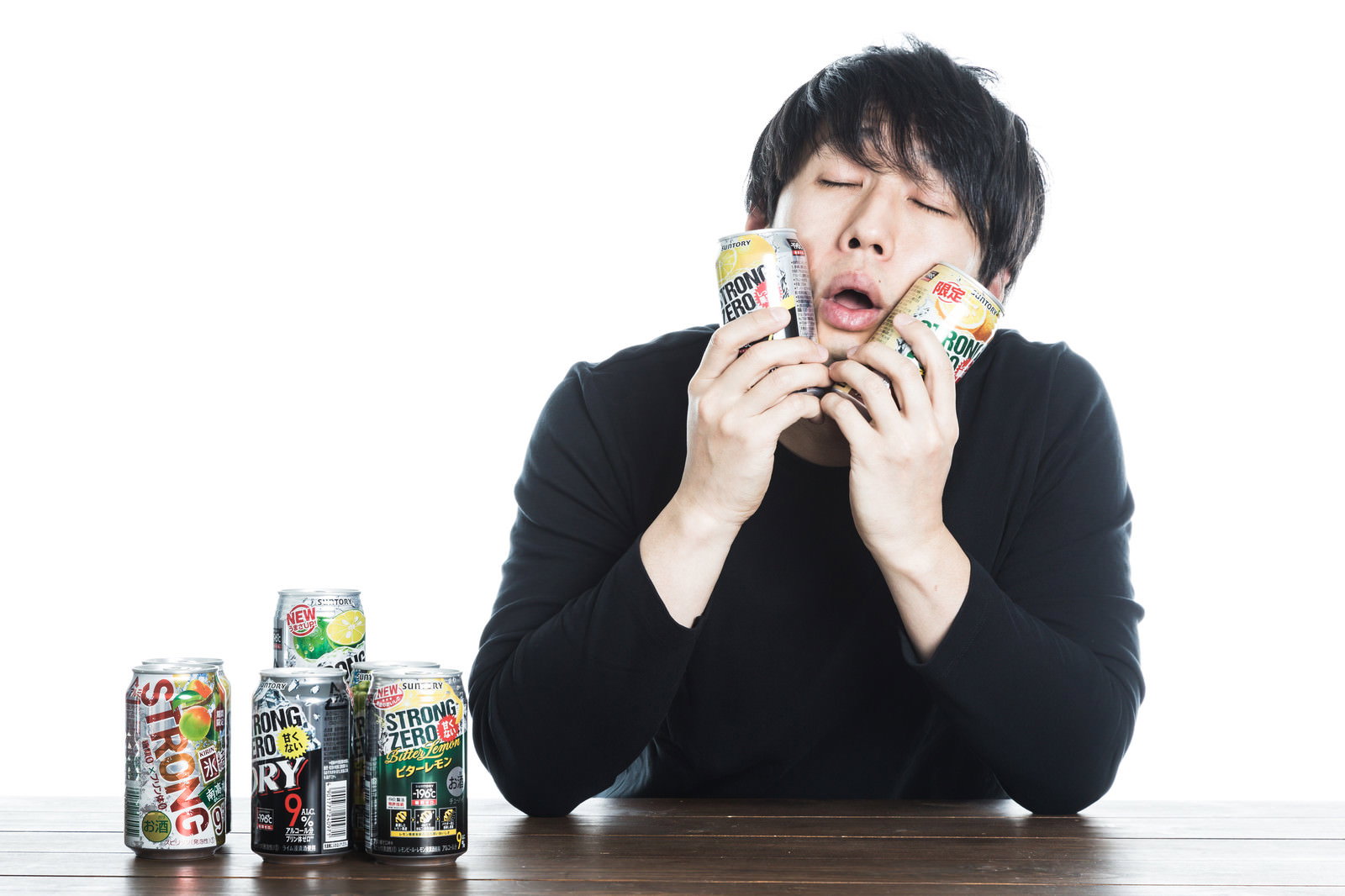 缶チューハイを両手で頬に当てて喜ぶ黒い服の男性［モデル：大川竜弥］