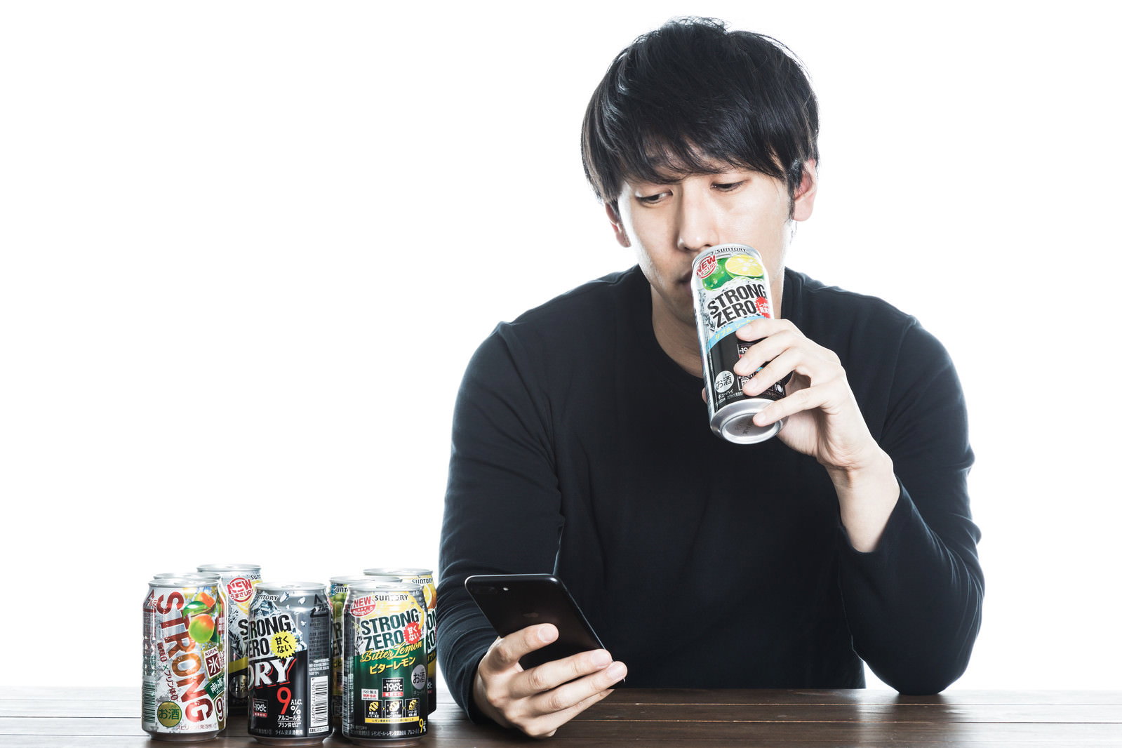 ストロングゼロを飲みながらスマートフォンを操作する男性［モデル：大川竜弥］