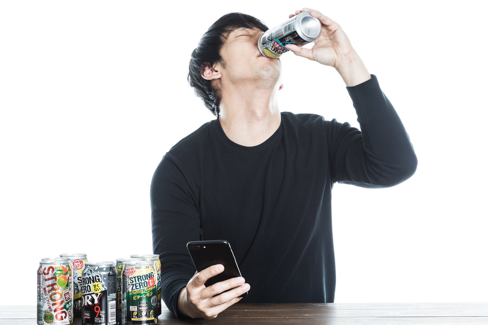 ストロングゼロを飲む黒い服の男性と複数の缶チューハイが並ぶ様子［モデル：大川竜弥］