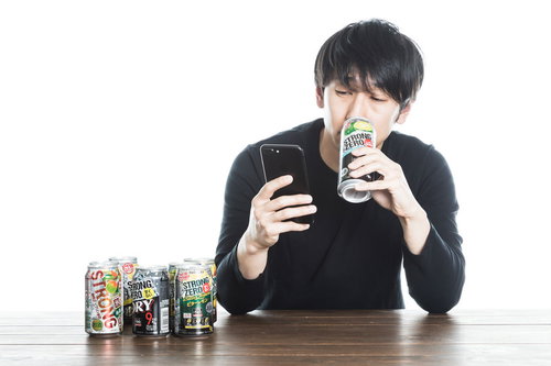 スマホを見ながらストロングゼロを飲む男性