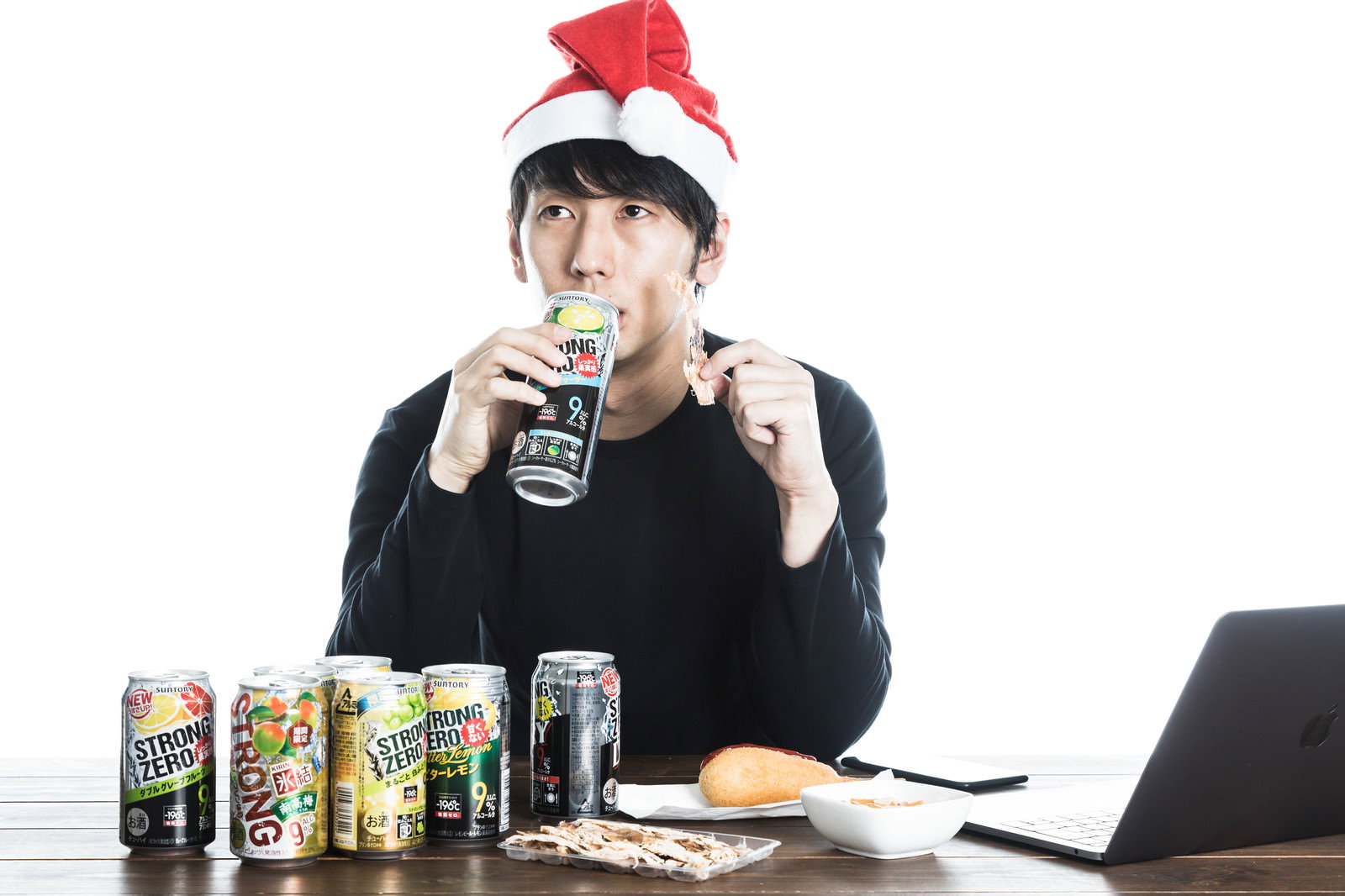 サンタ帽をかぶってテーブルで缶チューハイを飲む男性［モデル：大川竜弥］