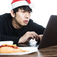 クリスマスイブに無料サンプル動画を見るサンタ帽子の男性の写真