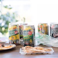 休日は昼間からストロングタイム。テーブルに並ぶ缶チューハイとおつまみの写真