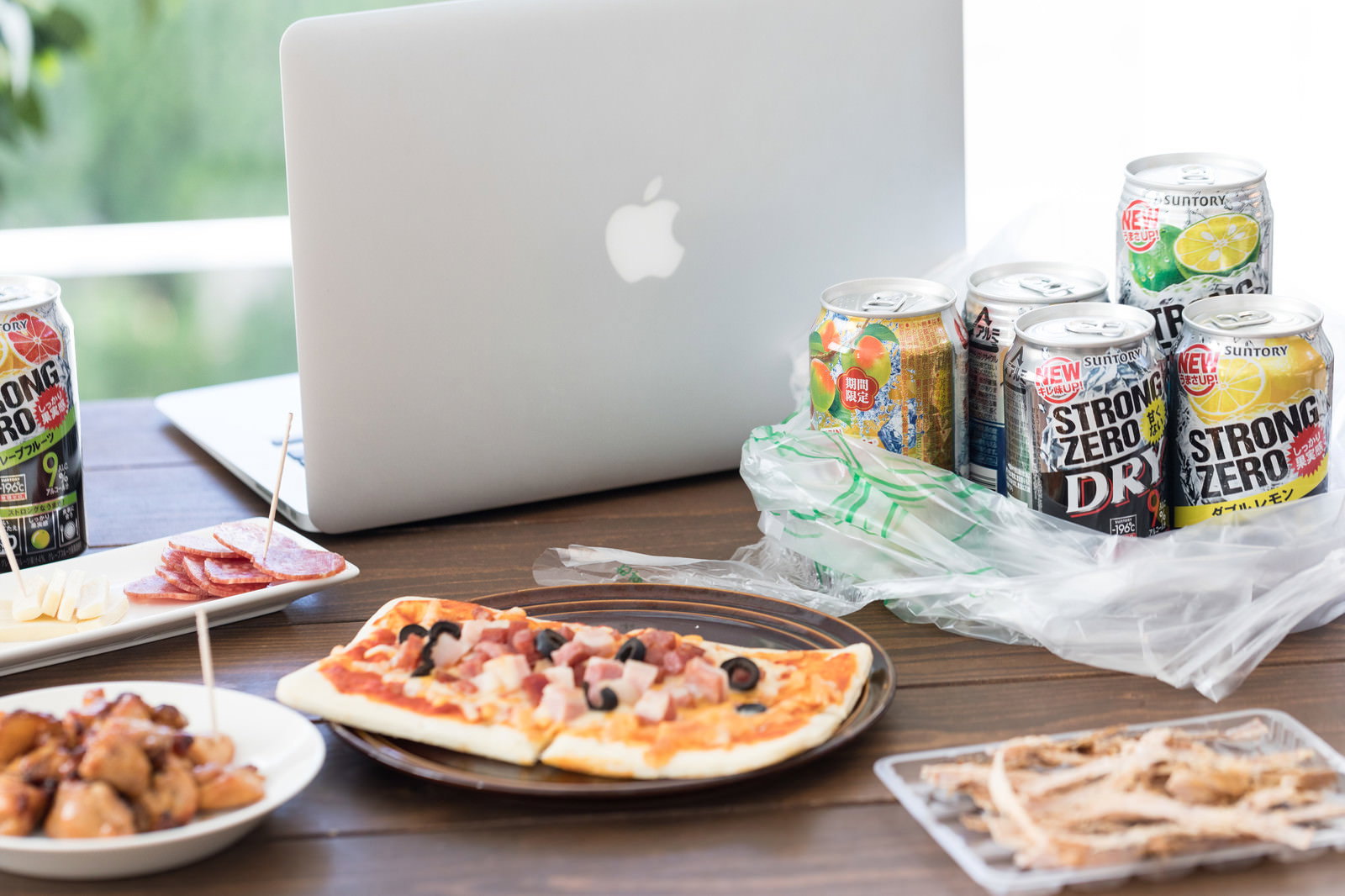 テーブルにMacBookとストロングゼロと食べ物が並ぶ