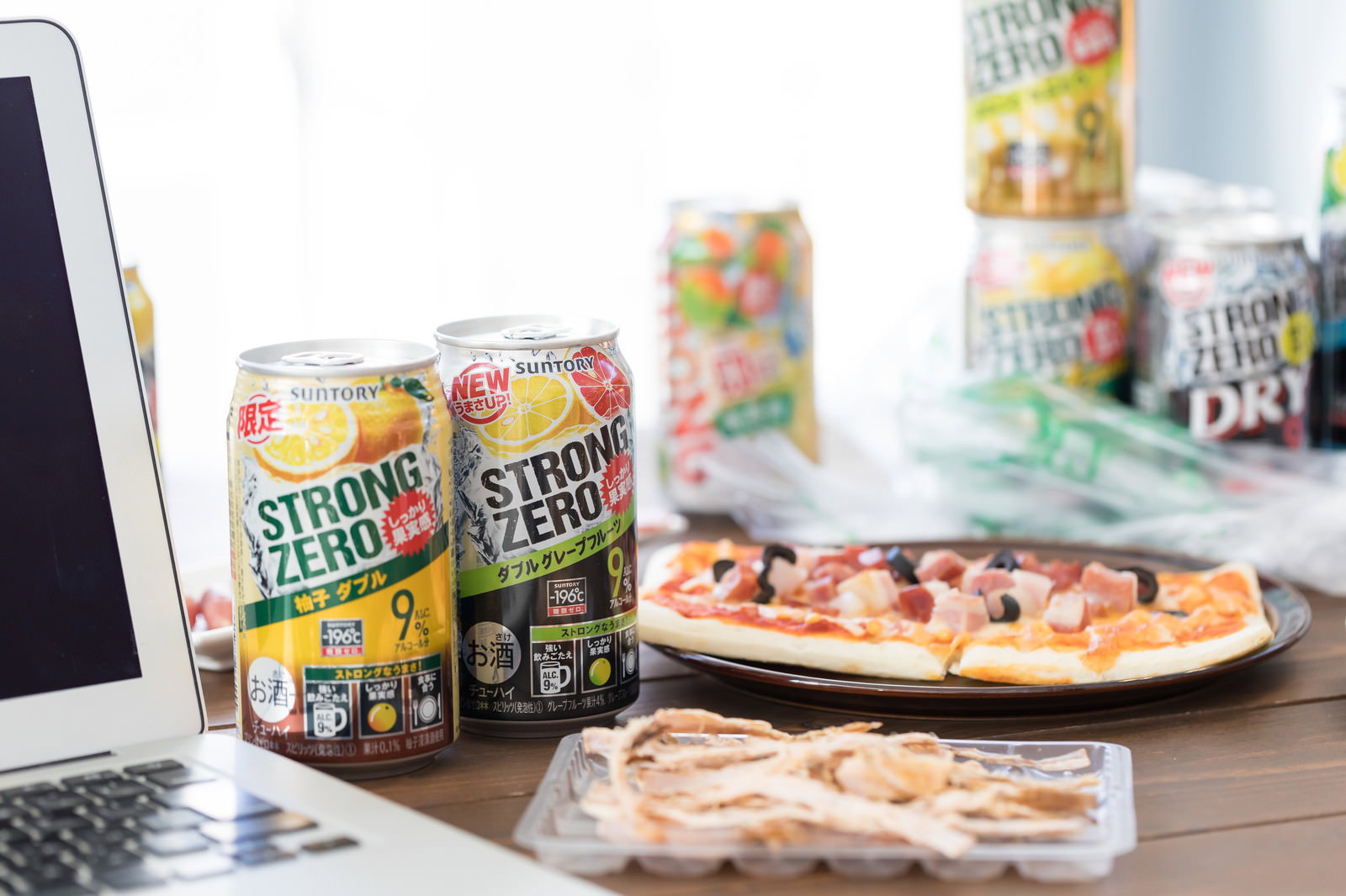 ノートパソコンとストロングゼロ缶、ピザが並ぶデスク