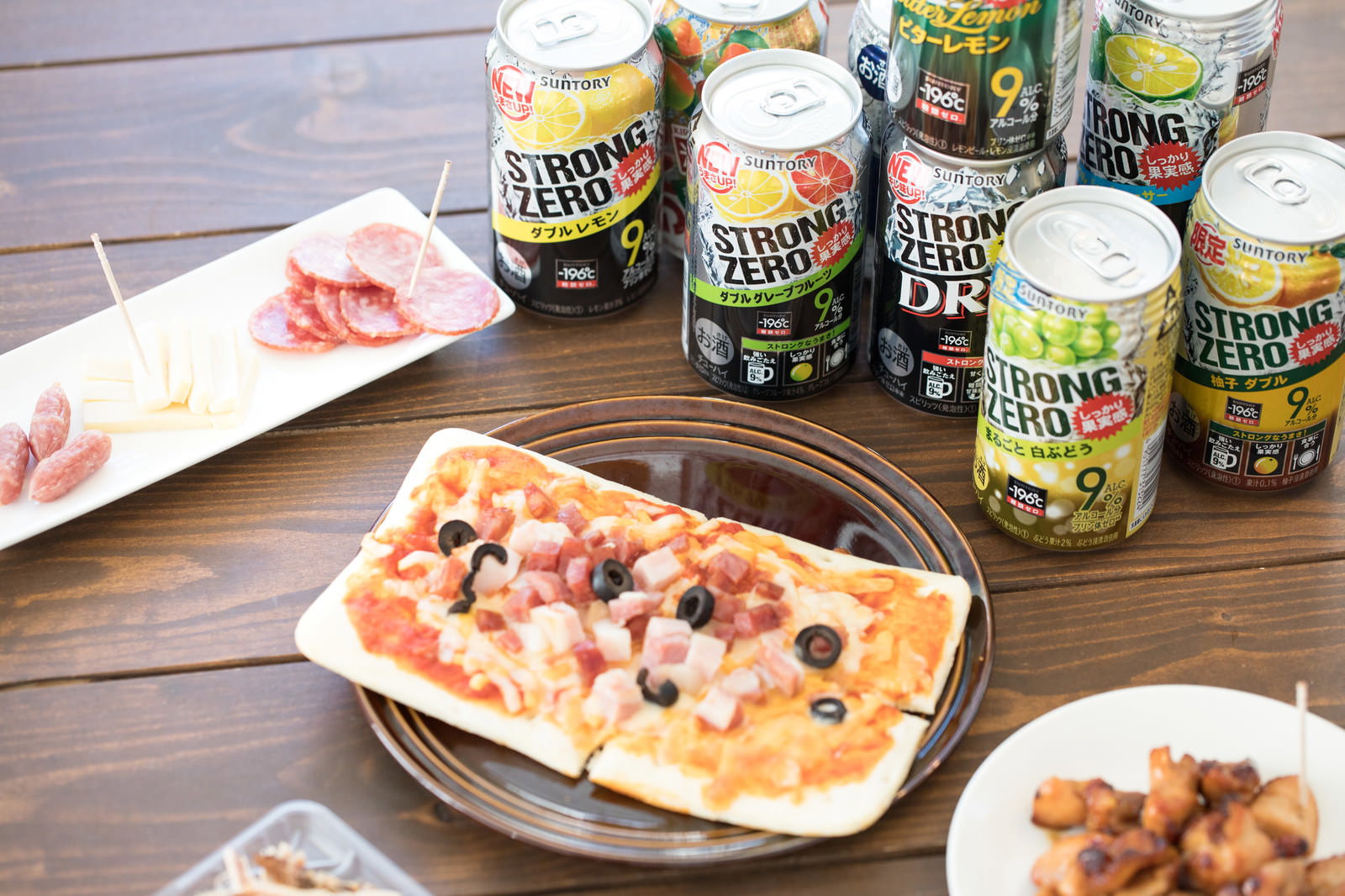 テーブルに並ぶストロングゼロの缶チューハイとピザやつまみ