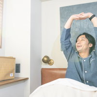 新しい朝がきた、希望の朝だ。ベッドで伸びをする男性の写真