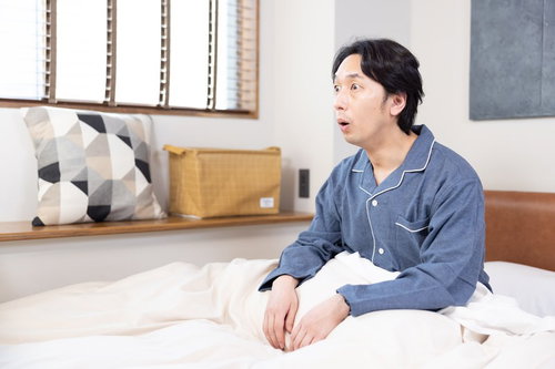 寝室で久々の快眠に驚く男性