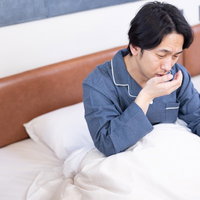 寝起きの口臭が気になり咳をする男性の写真