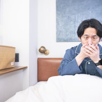ベッドの上で寝ても咳が止まらない男性の体調不良の写真