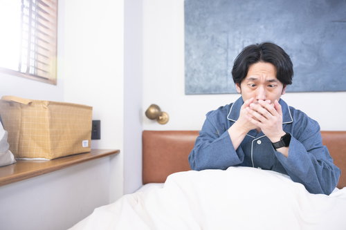 ベッドの上で寝ても咳が止まらない男性の体調不良