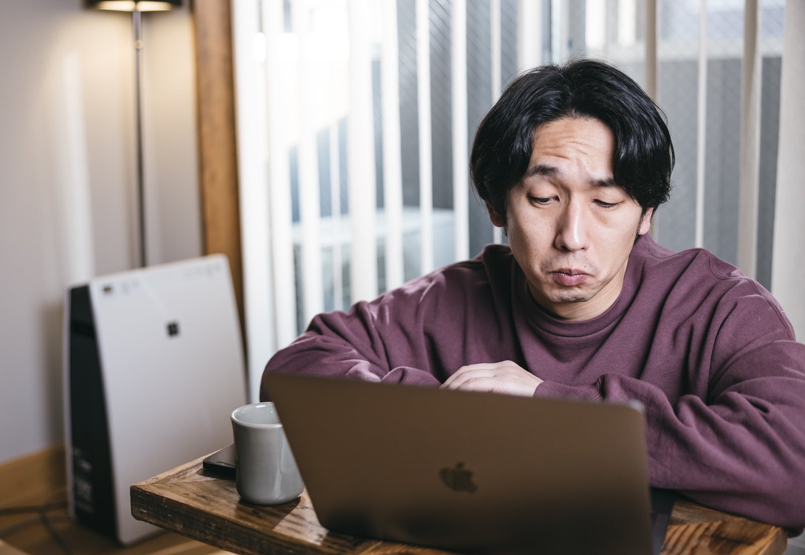 ヘッドフォンをつけて紫のシャツを着た男性がノートパソコンで作業している様子［モデル：大川竜弥］