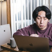 リモートワークはうんざり、紫シャツのエンジニアがヘッドフォンで作業の写真