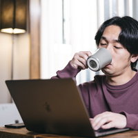 眠くてコーヒーをがぶ飲みするエンジニア男性の写真