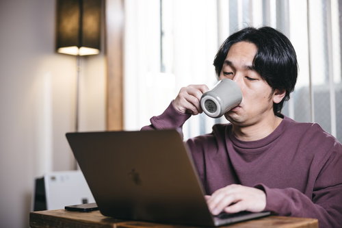 眠くてコーヒーをがぶ飲みするエンジニア男性