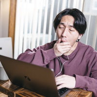 リモート会議中にうとうとしてあくびする男性の写真