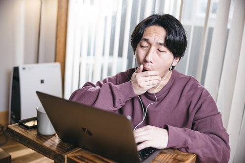 リモート会議中にうとうとしてあくびする男性