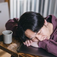 過労で机に寝落ちするエンジニア男性の写真