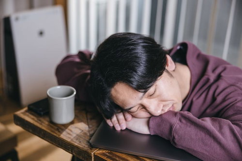 過労で机に寝落ちするエンジニア男性