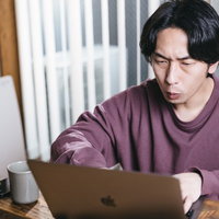 紫色のスウェットでリモートワークをするエンジニア男性の写真