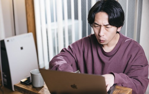 紫色のスウェットでリモートワークをするエンジニア男性