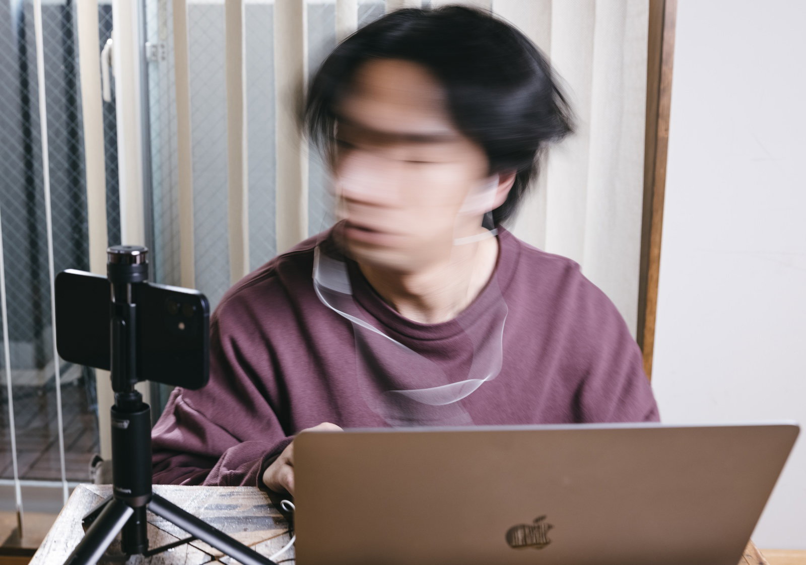紫色のトップスを着た男性がノートパソコンでリモート会議をしている［モデル：大川竜弥］