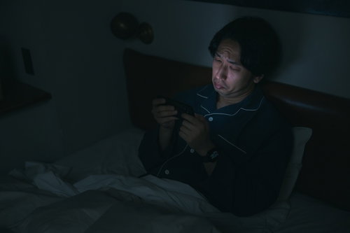 眠れなくてベッドでスマホ動画を見てしまう男性