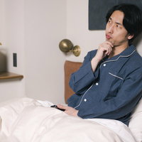 ベッドの上で一考する男性の写真
