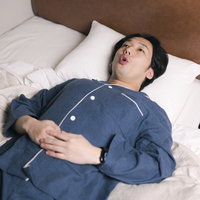 心地よい睡眠のためのリラックス、ベッドで腹式呼吸する男性の写真