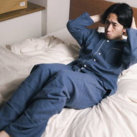 ベッドの上で腹筋を始める青いトレーニングウェアの男性の写真