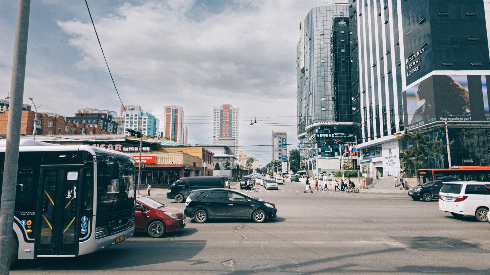 モンゴルの都市交差点を行き交う車やバスと建築物