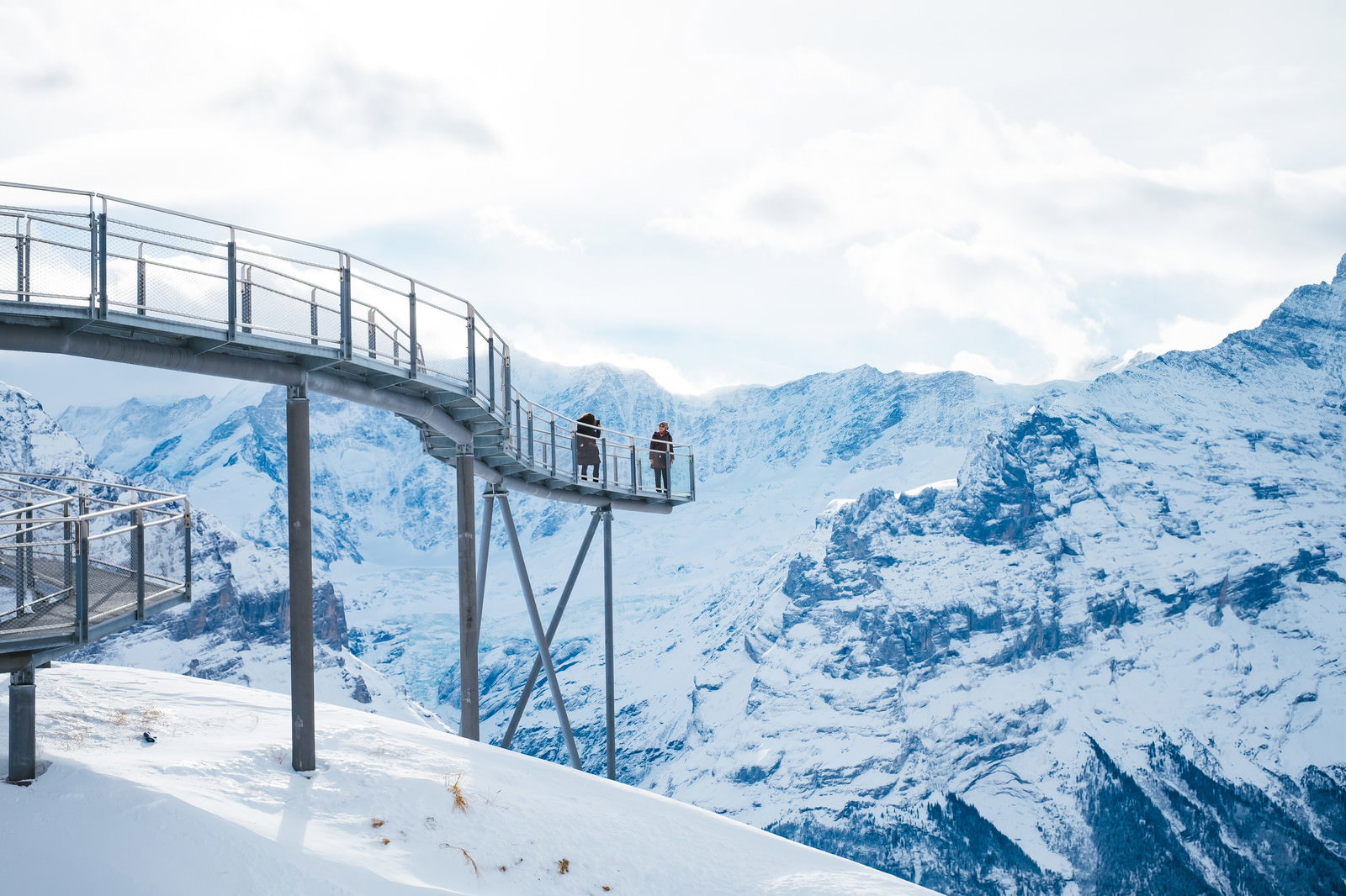 スイスのフィルスト・クリフウォークで雪山を背景に記念撮影する観光者