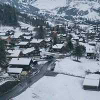 アルプスを背景にした雪に覆われたグリンデルワルトの山麓の街並みの写真