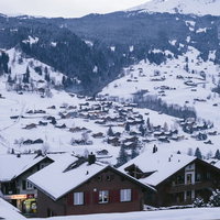 冬のグリンデルワルトの街並みと雪化粧したアルプスの山々の写真