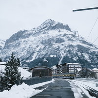 グリンデルワルト（スイス）を走行する電車と雪山の写真