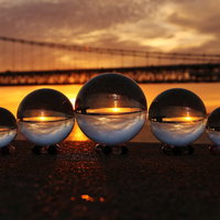 夕焼けが反射するガラス玉と橋の風景の写真